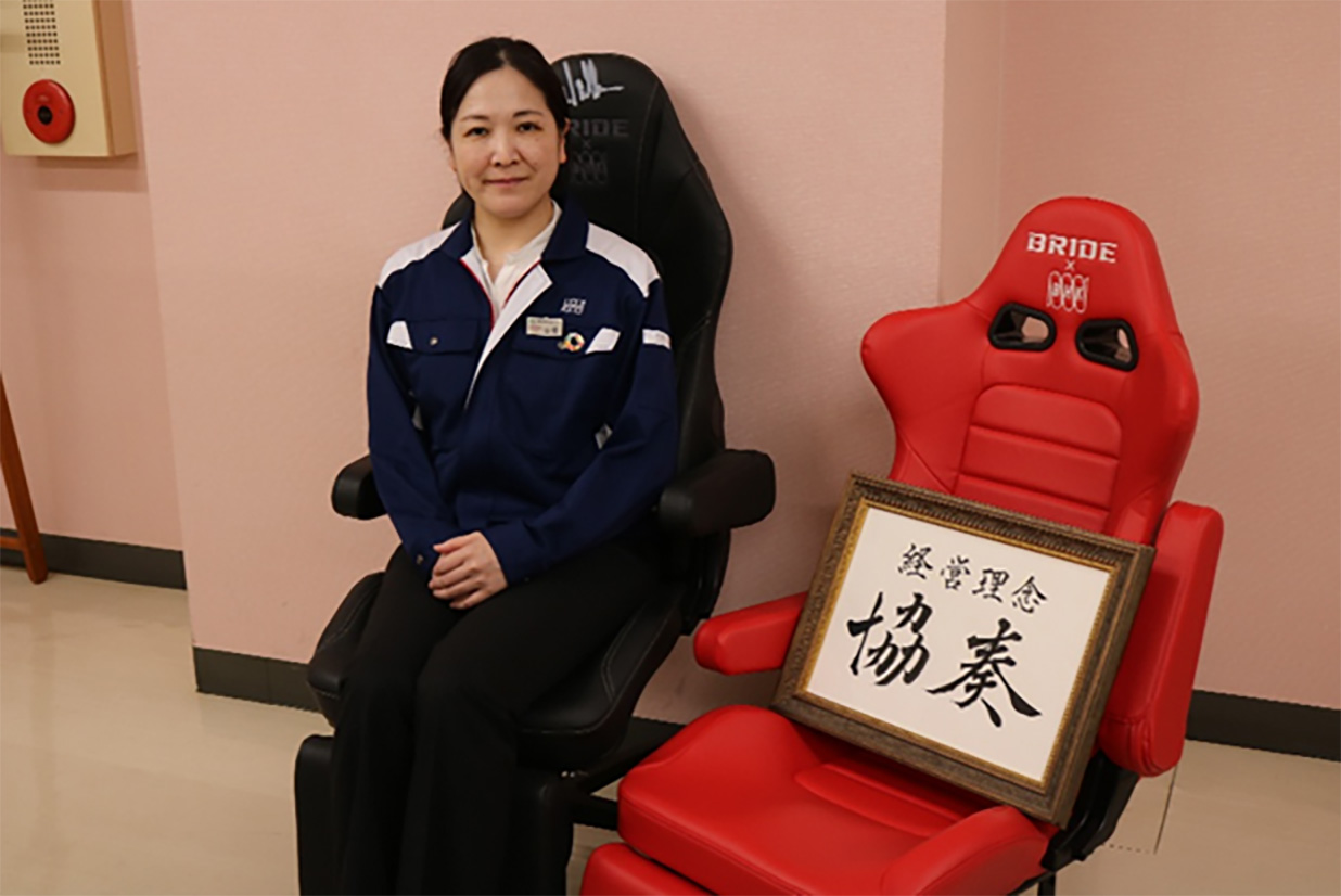 備前発条社長の山根さんの写真。経営理念の「協奏」のパネルを右に置く