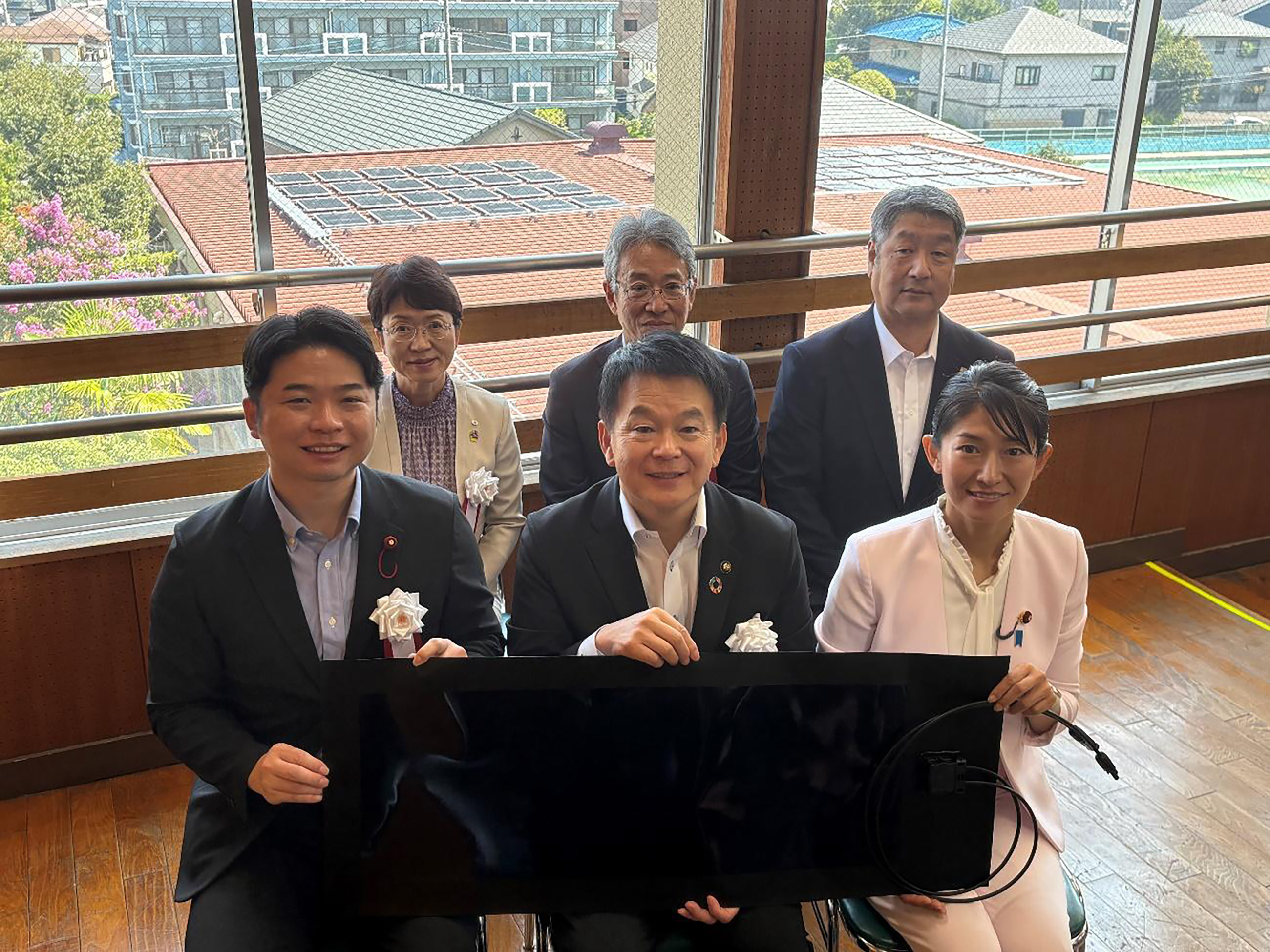 ペロブスカイト太陽電池のフィルムを持つさいたま市の清水勇人市長と環境省の森下千里政務官の写真