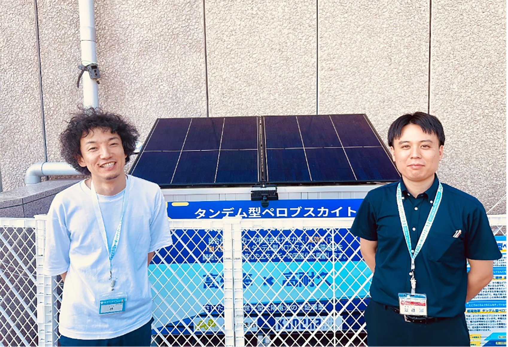 役所の入口に設置されているタンデム型ペロブスカイト太陽電池について説明するさいたま市環境局環境共生部ゼロカーボン推進戦略課の林勇希さんと渡辺悠也さんの写真